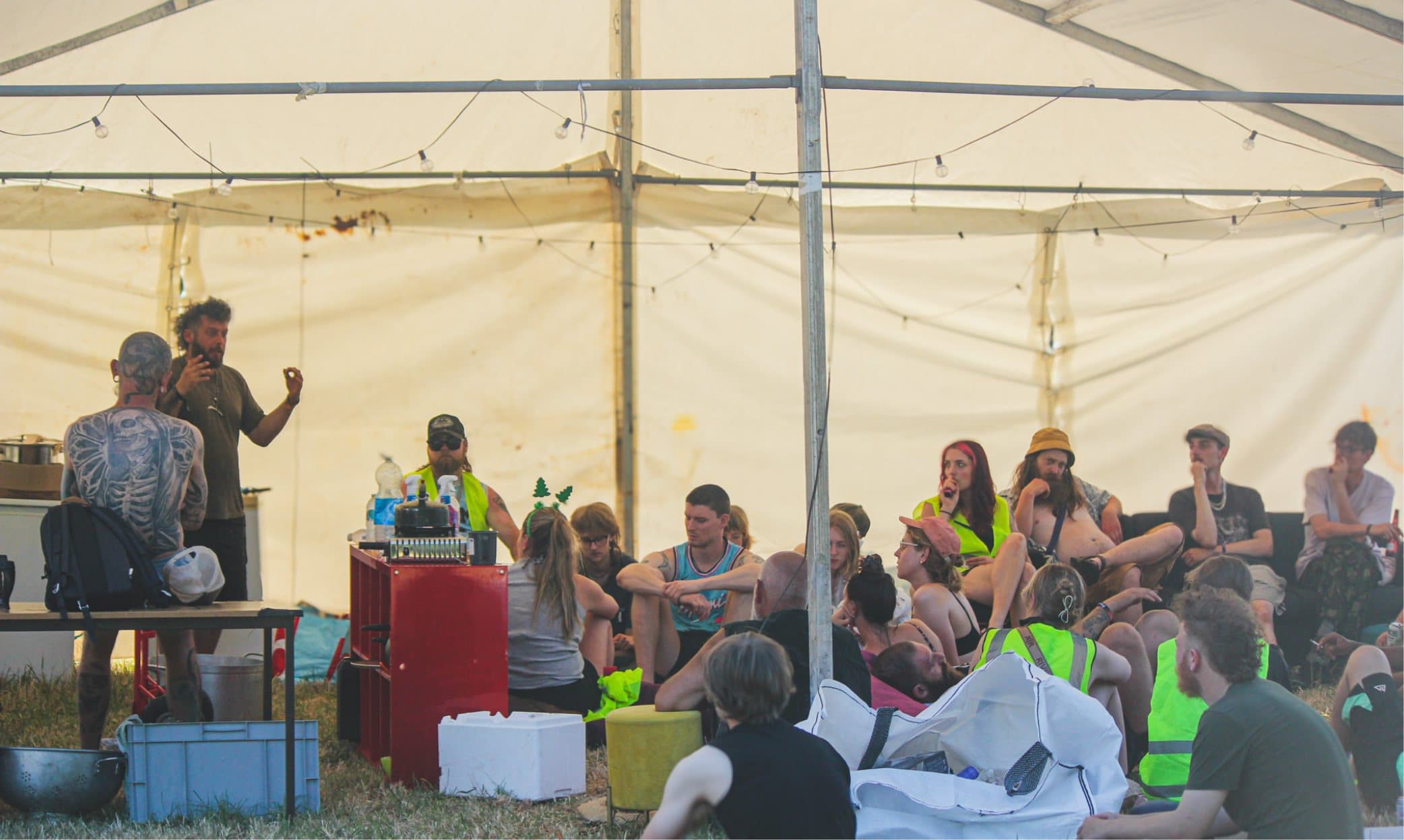 Crew sitting on the grass under the big top for the Saturday morning briefing.