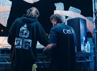 Crew rigging a stage at night under red and blue light